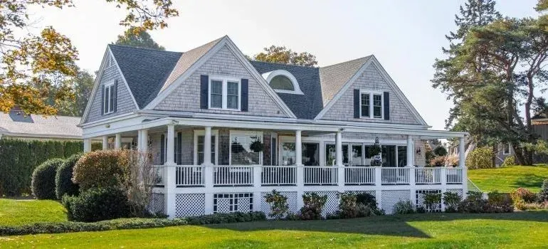 Gray shingled house with wraparound porch and lawn