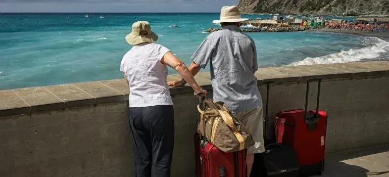 Older couple with suitcases overlooking turquoise sea