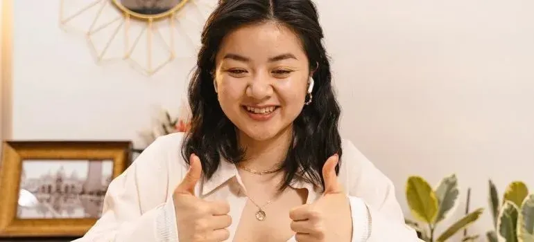 Woman giving two thumbs up during video call