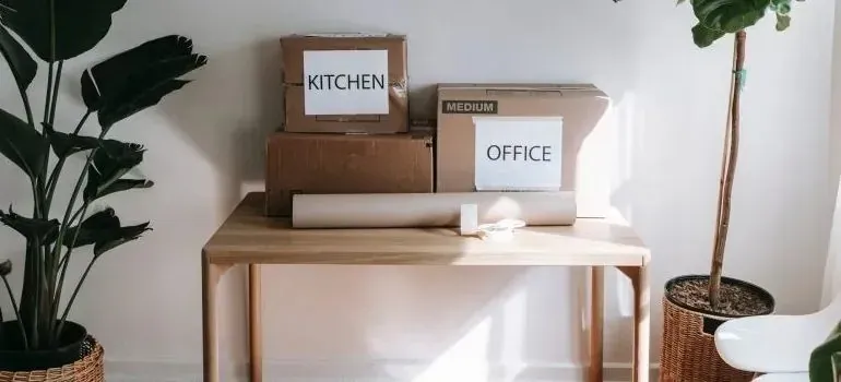 Moving boxes labeled kitchen and office on wooden table