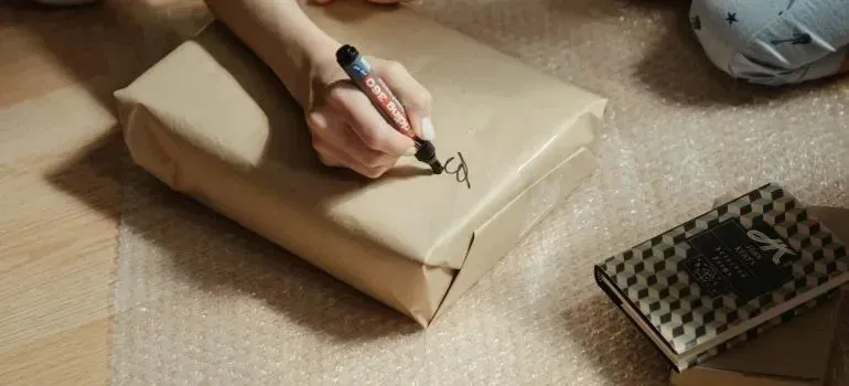 Hand labeling paper-wrapped parcel with black marker
