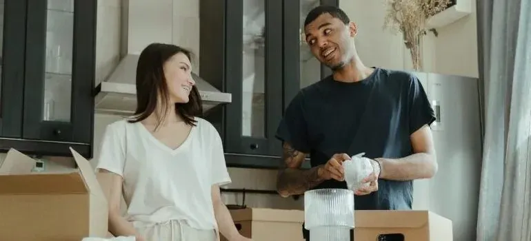 Couple unpacking cardboard boxes in kitchen