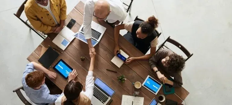 Overhead team meeting with handshake across wooden table