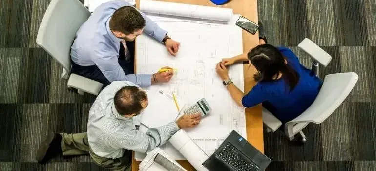 Overhead view of team reviewing blueprints at desk