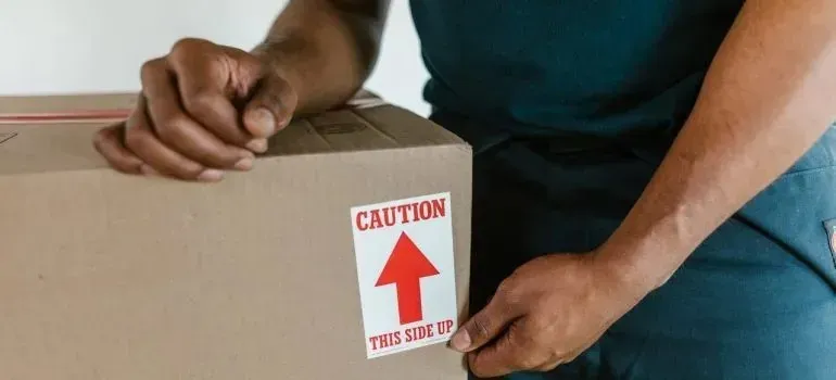 Man holding box with caution this side up sticker