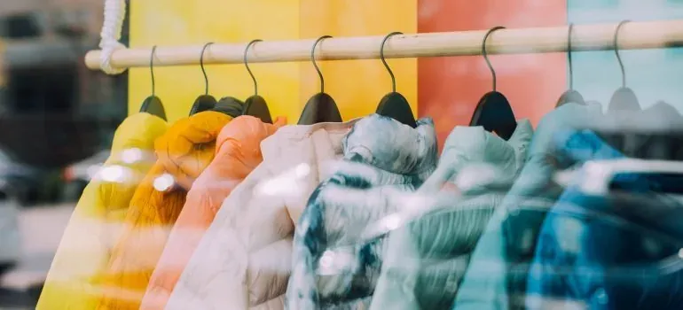 Colorful jackets on hangers behind glass