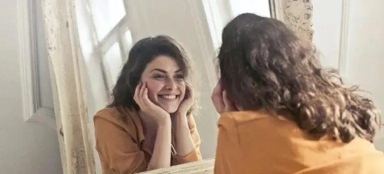 Smiling woman looking at herself in vintage mirror