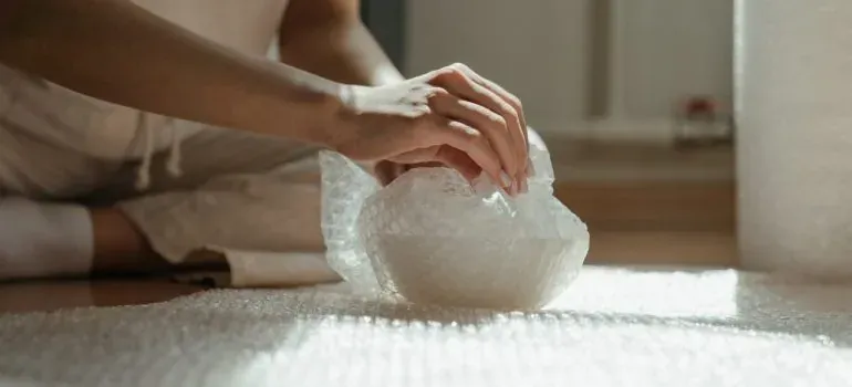 Hand wrapping bowl in bubble wrap
