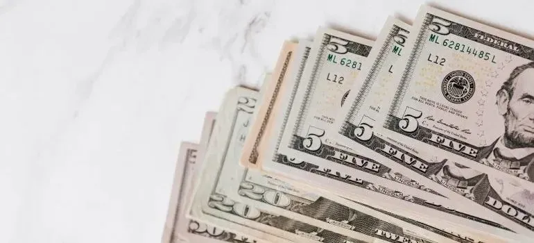 Fanned US dollar bills on white marble surface