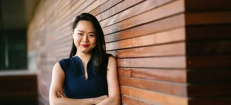 Confident woman with crossed arms against wooden wall