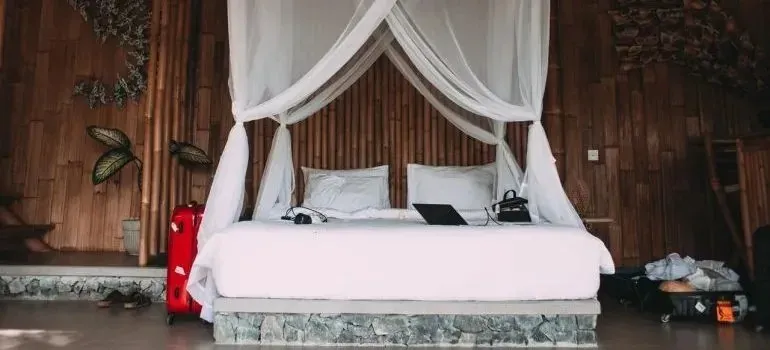 Canopy bed and red suitcase in bamboo bedroom