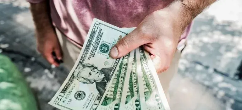 Man's hand holding fanned twenty-dollar bills outdoors