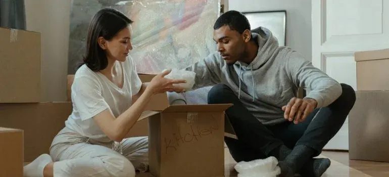 Couple unpacking kitchen box on floor