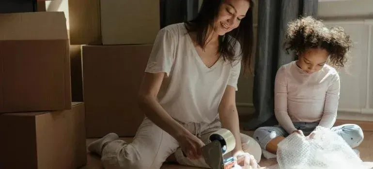 Mother and child taping moving boxes with bubble wrap