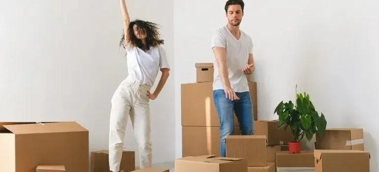 Young couple dancing among stacked moving boxes