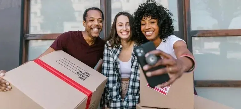 Three friends taking selfie with packed moving boxes