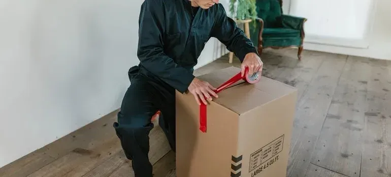 Mover in plain unbranded coveralls taping large box