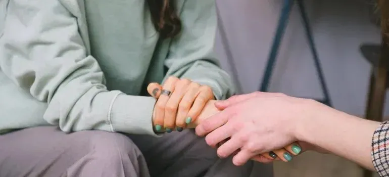 Two people holding hands in comforting gesture