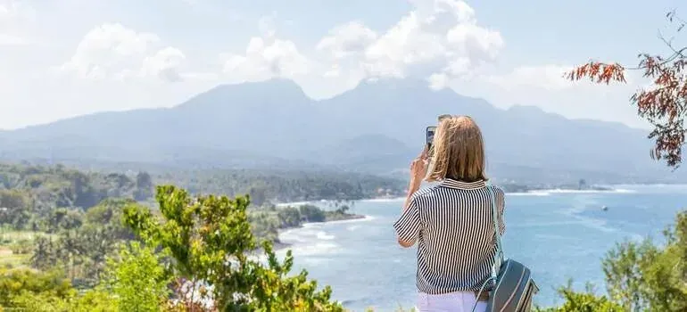Woman photographing coastal mountain view