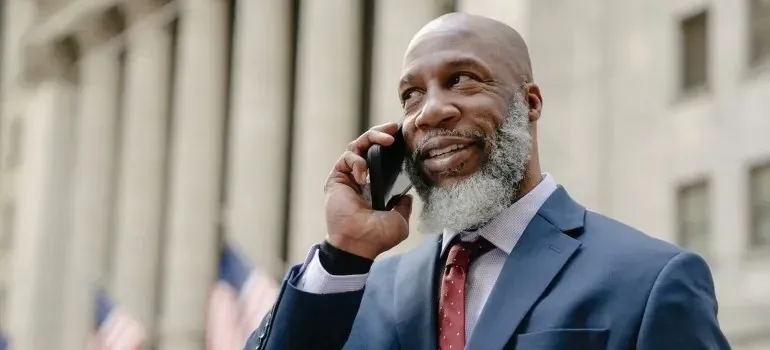 Bearded businessman in suit on phone, flags behind