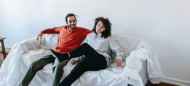 Couple relaxing on plastic-wrapped sofa in new home