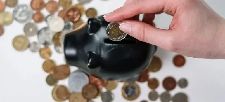 Hand dropping coin into black piggy bank