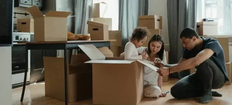 Family with child unpacking cardboard boxes at home