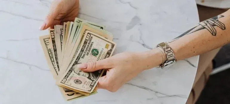 Hands counting fanned US dollar bills on table