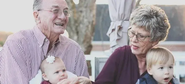 Grandparents holding baby and toddler grandchildren outdoors