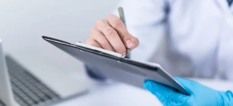 Gloved hands writing on clipboard