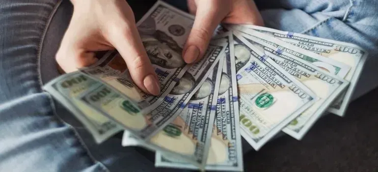 Hands fanning out spread of hundred-dollar bills