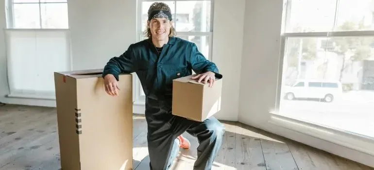 Kneeling mover with box in empty sunlit room