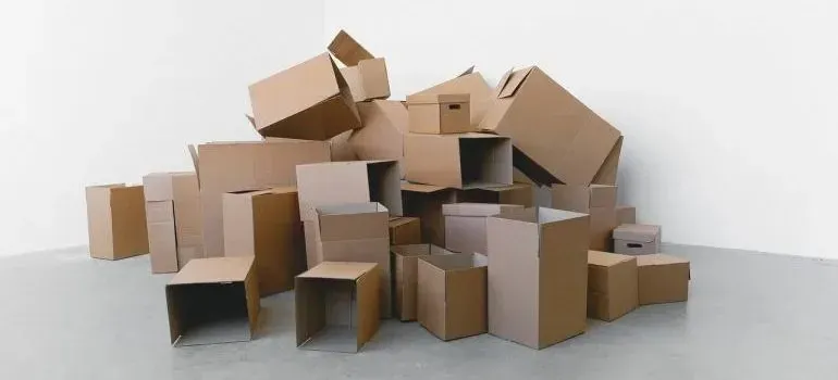 Pile of empty plain cardboard boxes against white wall