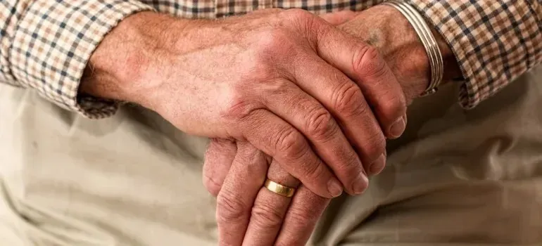 Elderly man's clasped hands with wedding ring and bracelet