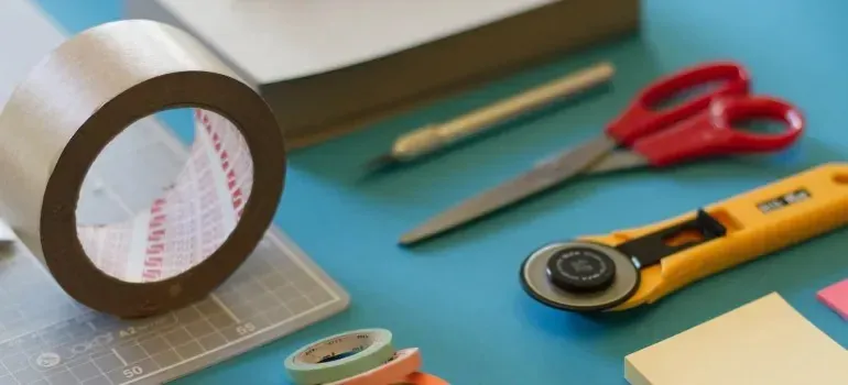 Craft flat lay: tape roll, scissors, rotary cutter, notes