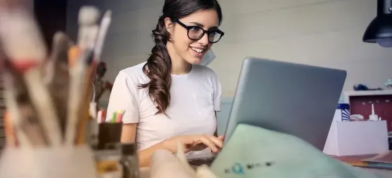 Smiling woman in glasses working on laptop at desk