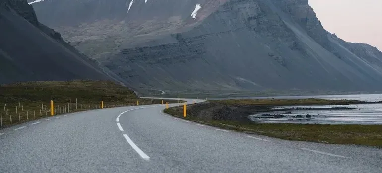 Winding empty road beneath steep coastal mountains