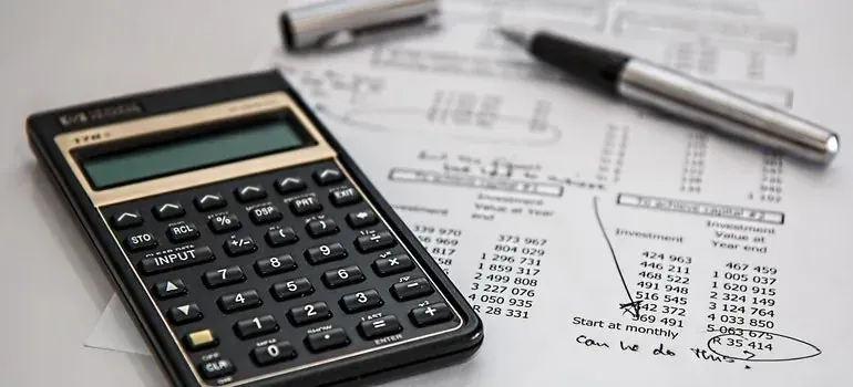 Calculator and pen on financial documents with handwritten notes