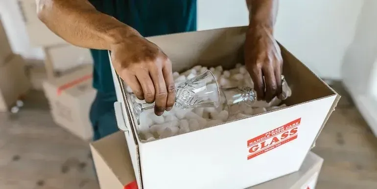 Mover packing crystal glasses into box with generic GLASS sticker