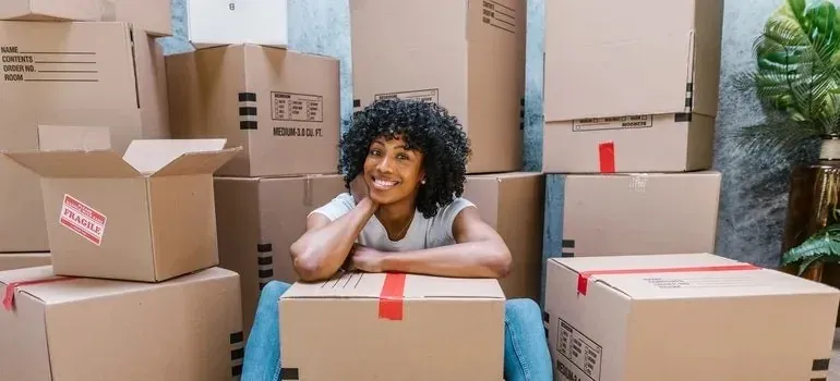 Smiling woman resting on cardboard boxes with fragile stickers