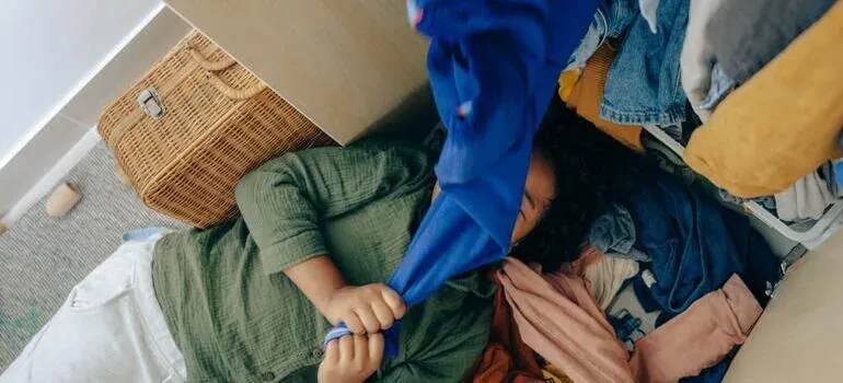 Child playing under pile of clothes