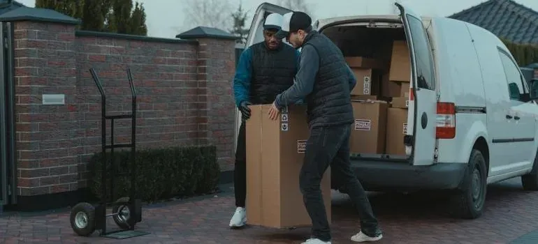 Two movers unloading tall box from unmarked white van