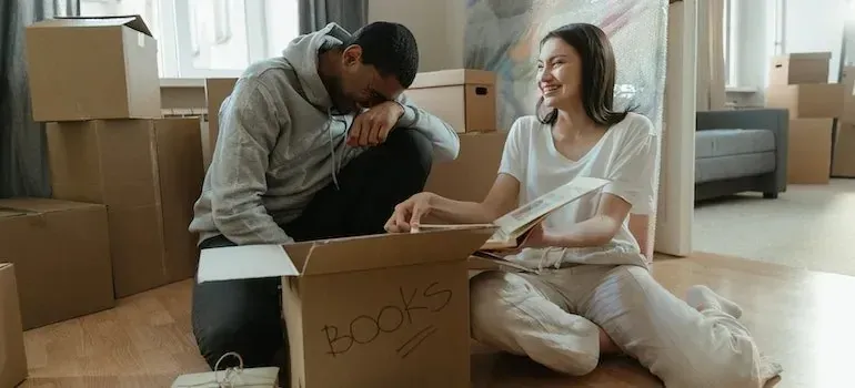 Laughing couple unpacking a box labeled books
