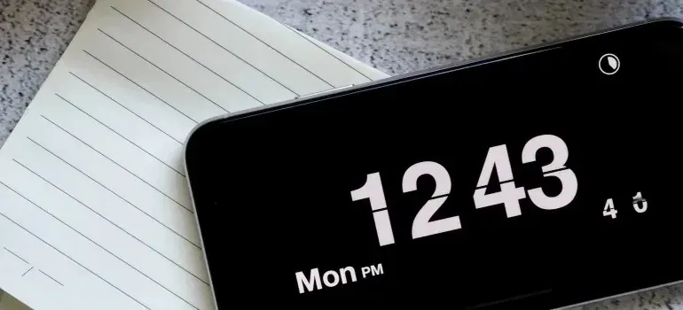Smartphone clock screen resting on a lined notepad