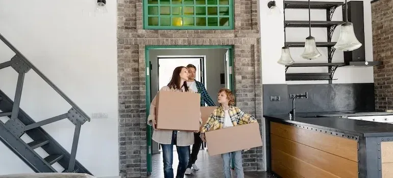 Family carrying boxes into a brick loft home