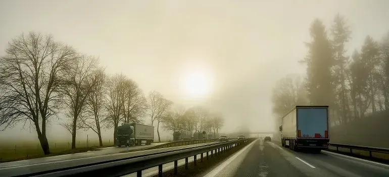 Semi trucks on a foggy highway at sunrise