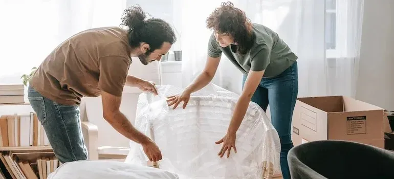 Couple wrapping furniture in bubble wrap while packing at home