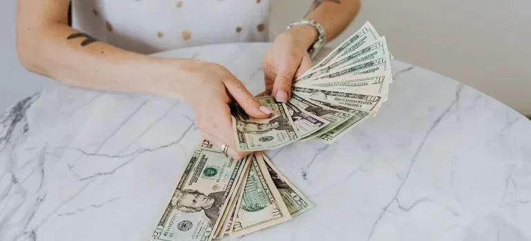 Woman fanning dollar bills at table