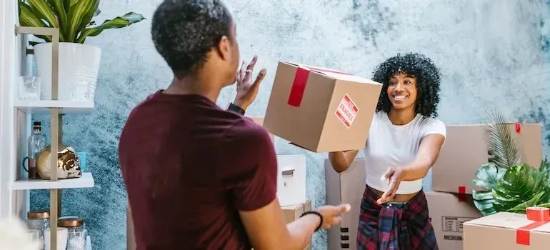 Man handing fragile labeled moving box to smiling woman