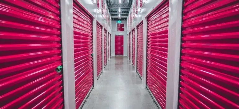 Storage facility hallway with rows of pink roll-up doors